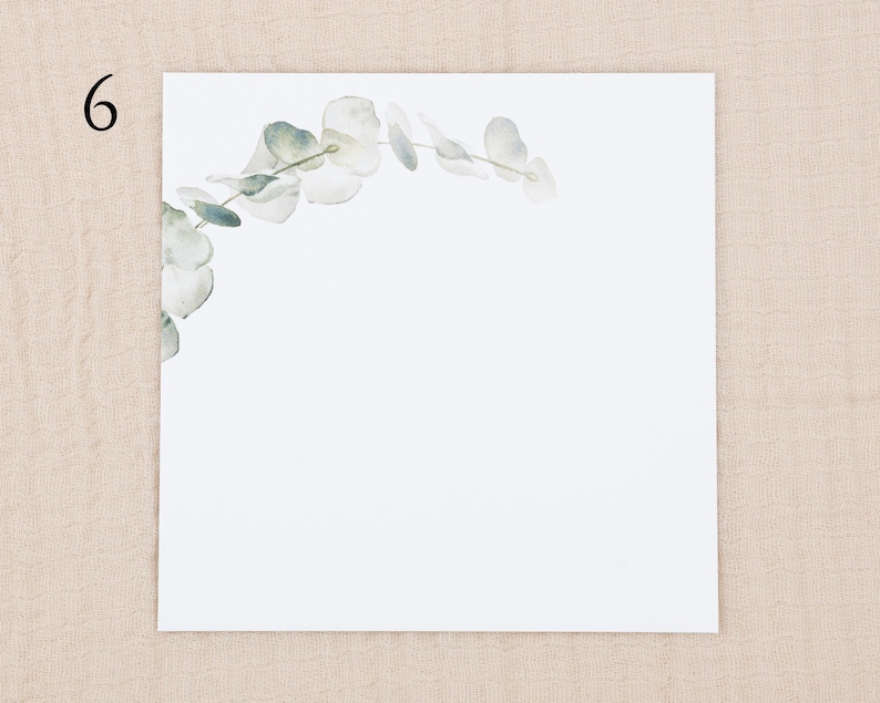 May include: A square white card featuring the number 6 in the top left corner and a delicate watercolor illustration of a curved eucalyptus branch with soft green and grey leaves extending from the left side across the top edge.