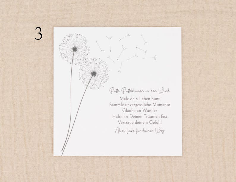 May include: A white square card featuring a dandelion illustration and German text. The dandelion design is in grey, with two full flower heads and several seeds floating away. The text is in a handwritten style.