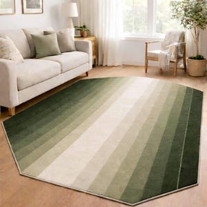 Pode incluir: Um tapete geométrico verde e bege com um design de listras gradientes. O tapete tem uma forma hexagonal única e é colocado em um piso de madeira. A paleta de cores do tapete inclui tons de verde e bege.