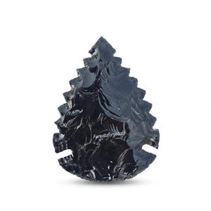 Puede incluir: Una punta de flecha de obsidiana negra con una superficie texturizada. La punta de flecha tiene forma de hoja con una punta y dos muescas en la base. El texto "Forestofcrystals" es visible.