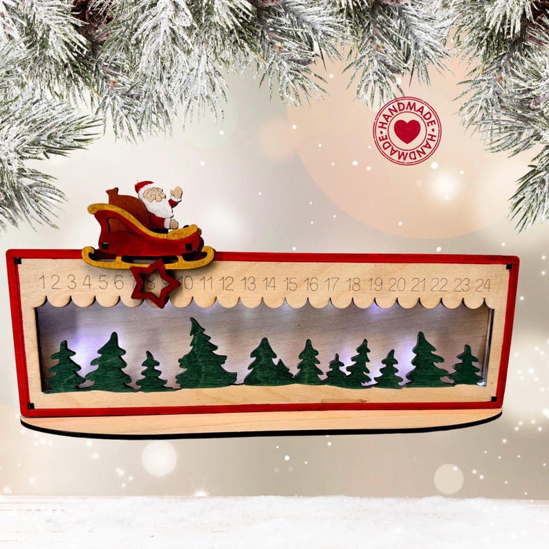 May include: A wooden Christmas advent calendar featuring a red frame, a cutout of Santa in a sleigh, and a numbered track from 1 to 24. The interior displays a layered forest of green trees illuminated by internal lights, set against a light wood background.