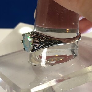 Puede incluir: Un anillo de plata con una piedra de &oacute;palo ovalada engastada en un dise&ntilde;o de filigrana.