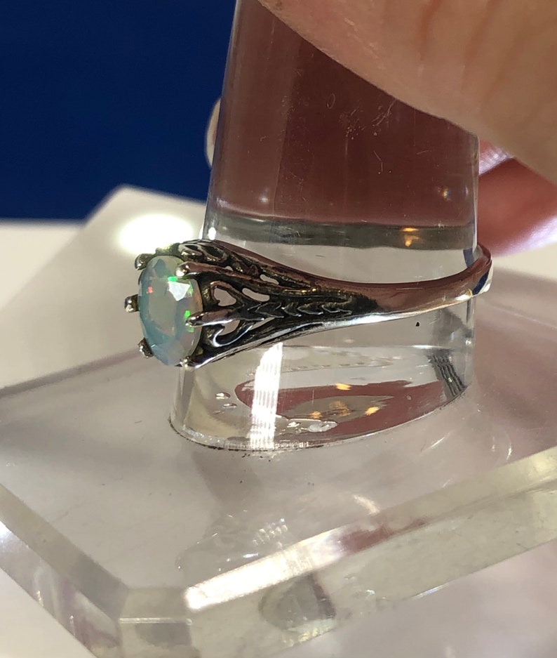 Puede incluir: Un anillo de plata con una piedra de &oacute;palo ovalada engastada en un dise&ntilde;o de filigrana.