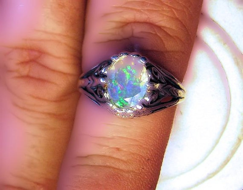 Puede incluir: Un anillo de plata con una piedra preciosa de &oacute;palo de forma ovalada. El &oacute;palo presenta un arco&iacute;ris de colores, incluyendo verde, azul y morado.