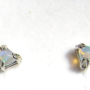 May include: A pair of silver earrings with a white opal gemstone in a triangular setting.