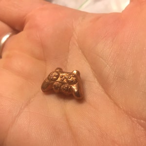 May include: A small, gold-colored, metal video game controller charm.