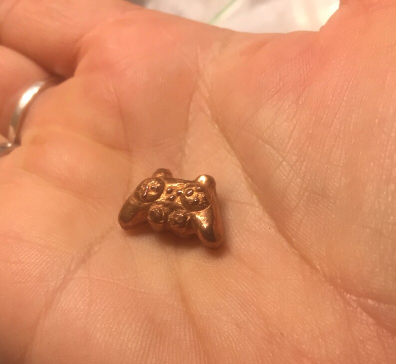 May include: A small, gold-colored, metal video game controller charm.