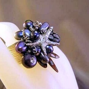 May include: A gold ring with a cluster of dark purple and black pearls, a silver starfish, and other decorative elements.