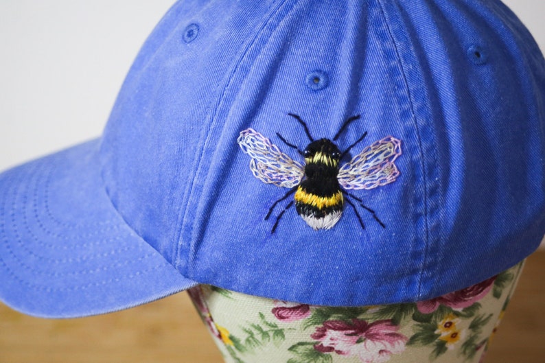 Handstitched bumble bee on a corn flower blue baseball cap. Featuring beaded eyes and delicately stitched wings.