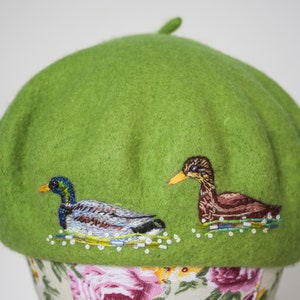 Vibrant green pure new woolmark beret with kitsch hand embroidered mallard ducks by Cherith Brown. The beret has been hand embellished with some glass beads to give the impression of water.