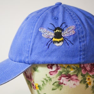 Handstitched bumble bee on a corn flower blue baseball cap. Featuring beaded eyes and delicately stitched wings.