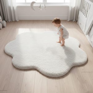 以下が含まれることがあります： 子供部屋にある、ふわふわとした白い雲型のラグ。 ラグは柔らかい素材でできており、明るい色の木の床に置かれています。 白いロンパースを着た赤ちゃんがラグの上に立っています。 部屋にはベビーベッドと窓があります。