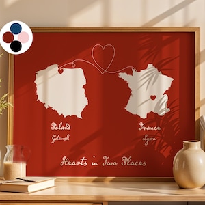 May include: A framed print with a red background shows white outlines of Poland and France, linked by a heart-shaped line. The text "Poland Gdansk" and "France Lyon" is below the maps, with "Hearts in Two Places" below.