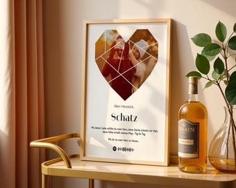 Könnte beinhalten: Gerahmter Druck mit einer herzförmigen Fotocollage. Der Druck zeigt das deutsche Wort "Schatz" und Text darunter. Eine Flasche Likör und eine Vase mit Grün stehen auf einem goldenen Tisch neben dem Druck.