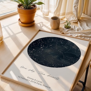 Peut inclure: Une impression encadr&eacute;e repr&eacute;sentant une carte c&eacute;leste bleu fonc&eacute; avec des &eacute;toiles blanches. L'impression comprend le texte "One sky. Two hearts." et les noms "Emma & Lucas" avec la date "14 f&eacute;vrier 2018 Paris, France."