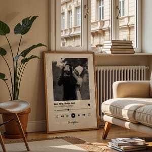 Könnte beinhalten: Ein gerahmter Schwarz-Weiß-Druck mit einem Paar, deren Gesichter verdeckt sind. Der Druck hat ein Musikplayer-Oberflächendesign mit dem Text "Your Song Choice Here" und "For a lifetime". Der Rahmen ist hellbraun.