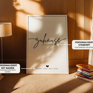 May include: A framed print with the word "Zuhause" in cursive script, along with a location and names. The print is displayed against a wooden wall, with a lamp and books in the background.