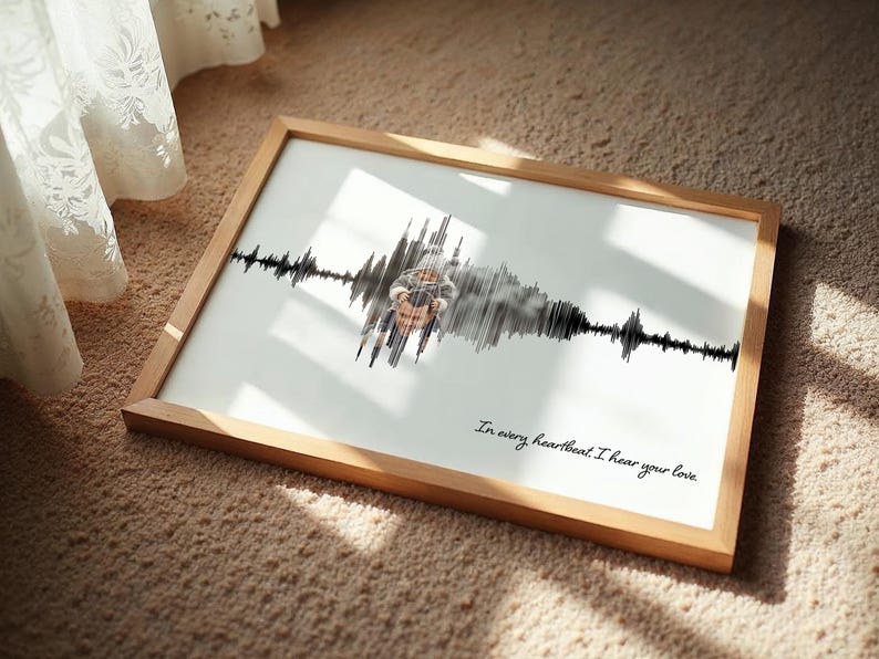 Puede incluir: Una impresi&oacute;n enmarcada con un marco de madera, que presenta un dise&ntilde;o de onda de sonido. La impresi&oacute;n tiene un fondo blanco con un patr&oacute;n de onda de sonido negro y una foto en el centro. El texto "In every heartbeat I hear your love" est&aacute; escrito en cursiva.