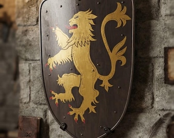 Puede incluir: Un escudo de madera marrón oscuro con un gran león rampante pintado en dorado, con lengua y garras rojas. El escudo tiene un borde de metal, tachuelas decorativas a lo largo de los bordes y un soporte de metal en la parte superior central.