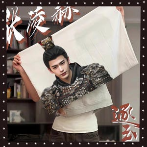 Può includere: Un tessuto rettangolare bianco con un ritratto di un uomo in armatura ornata e una corona. L'uomo ha i capelli scuri e guarda lo spettatore. I caratteri cinesi sono visibili in alto a sinistra e in basso a destra.