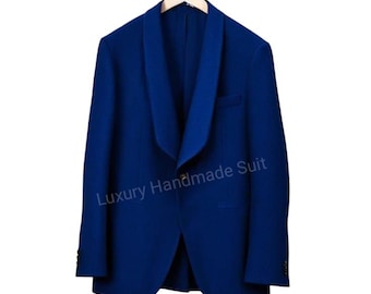 May include: A vibrant blue blazer with a shawl collar, hanging on a wooden hanger. The jacket has a single-button closure and a small pocket. The text "Luxury Handmade Suit" is printed on the front.