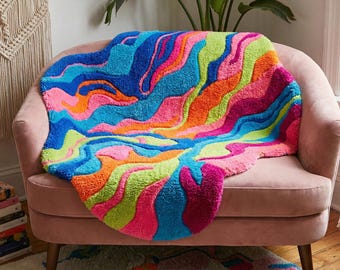 May include: A vibrant, colorful rug with a wavy, abstract design in shades of blue, pink, orange, and green. The rug is placed on a pink armchair, creating a bold statement piece for home decor.