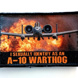 May include: Rectangular patch featuring an A-10 Warthog aircraft against a fiery background. The text "I SEXUALLY IDENTIFY AS AN A-10 WARTHOG" is printed in orange. The patch has a black border.