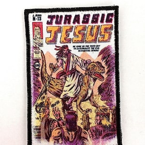 Peut inclure: Un écusson rectangulaire à bordure noire avec une illustration de style bande dessinée. Le titre "JURASSIC JESUS" est affiché en grandes lettres jaunes. L'image représente Jésus chevauchant un dinosaure, avec du texte en dessous.