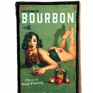 Peut inclure: Un écusson rectangulaire avec un fond vert et une bordure noire. L'écusson présente une illustration de style vintage d'une femme avec une boisson, une bouteille de bourbon et le texte "The dames of Bourbon" et "Choose Your Poison."