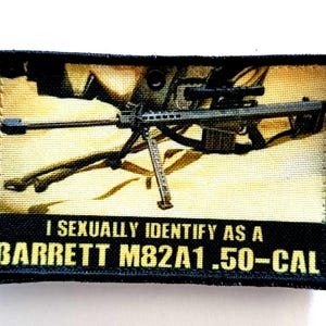 Peut inclure: Écusson rectangulaire avec une illustration détaillée d'un fusil Barrett M82A1 .50-Cal avec une lunette, sur fond beige. Le texte "I SEXUALLY IDENTIFY AS A BARRETT M82A1 .50-CAL" est affiché en lettres jaunes en gras.