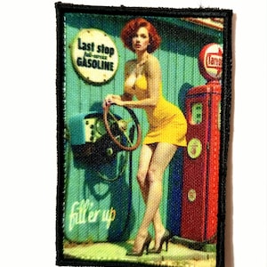 May include: Embroidered patch featuring a retro gas station scene. A woman in a yellow dress leans against a vintage gas pump. The patch includes the text "Last stop gasoline" and "fill 'er up". The patch has a black border.