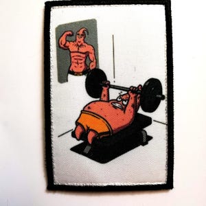 Puede incluir: Parche rectangular con un personaje de dibujos animados levantando pesas. El personaje rosa lleva pantalones cortos naranjas. Otro personaje de dibujos animados flexiona en el fondo. El parche tiene un borde negro y un fondo blanco.