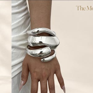 Set de brazaletes cuff escultóricos plateados, stack de bangles statement pulidos