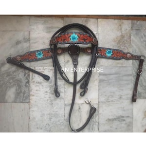May include: A brown leather horse bridle set with intricate floral tooling and turquoise accents. The set includes a headstall, breast collar, and reins. The text "RN ENTERPRISE" is visible on the product.