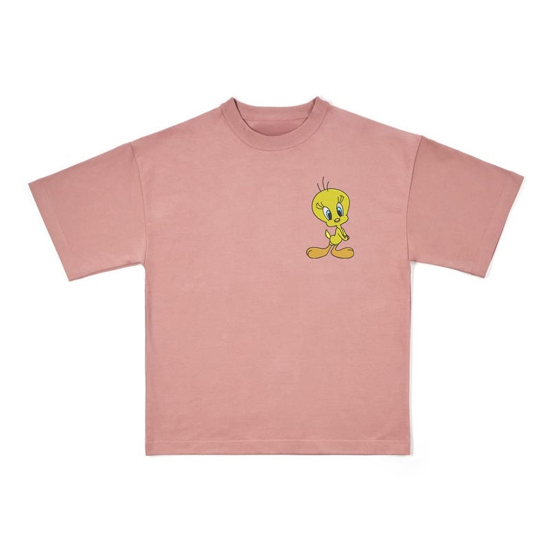 May include: A dusty rose-colored t-shirt featuring a small graphic of Tweety Bird. The cartoon character is yellow with black outlines and is positioned on the left chest area of the shirt. The shirt has short sleeves and a crew neck.