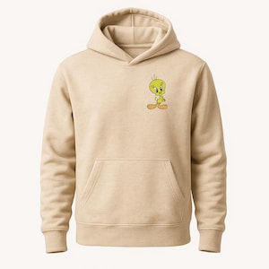 May include: Beige hoodie featuring a front kangaroo pocket and a drawstring hood. The hoodie has a small embroidered image of Tweety Bird on the upper left chest. The cartoon character is yellow with orange feet and a black outline.