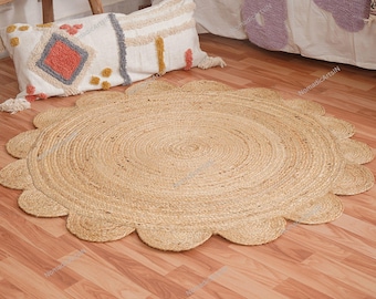May include: A circular jute rug with a scalloped edge. The rug is light brown and has a concentric circular design. A decorative pillow with a geometric pattern and tassels is in the background.