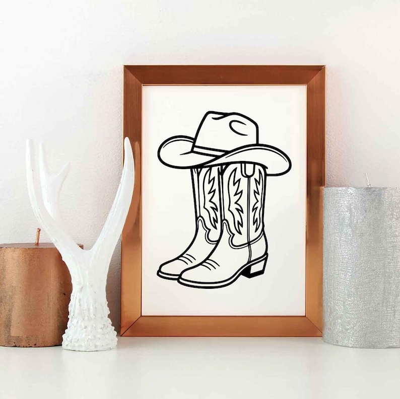 May include: Black and white line art print of a cowboy hat resting on top of a pair of cowboy boots. The boots have decorative stitching. The artwork is in a gold-colored frame.