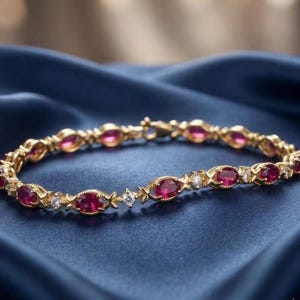 May include: A gold link bracelet featuring a repeating pattern of oval-cut deep red rubies and small round-cut clear diamonds. The metal links are textured with a delicate cross-hatch design between each gemstone, secured with a metal clasp.