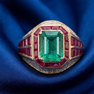 Puede incluir: Un anillo de oro con una gran esmeralda de corte esmeralda en el centro, rodeada por un borde rectangular de rubíes rojos de corte cuadrado y una capa exterior de diamantes blancos de corte baguette en una banda de metal estructurada.