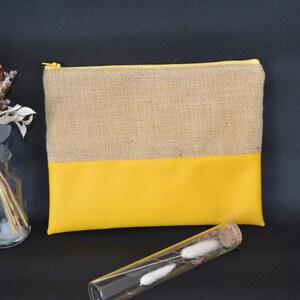 May include: A rectangular pouch with a natural burlap top and a bright yellow bottom. The pouch has a gold zip closure. A clear glass vase with dried flowers and a glass tube with dried flowers are also in the image.