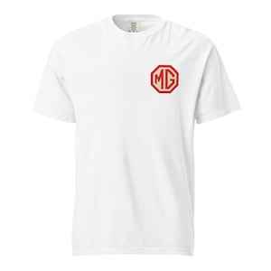 May include: White t-shirt with a red and white MG logo on the left chest. The logo is an octagon shape with the letters "MG" inside. The shirt has short sleeves and a crew neck.