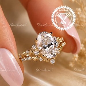 May include: A gold ring set featuring a large oval-cut center stone and smaller round accent stones. The band has a textured, vine-like design. An IGI International Gemological Institute seal is visible in the upper right corner of the image.