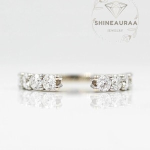 May include: A silver-toned open ring featuring a series of small, round, clear stones set along both ends of the band. The jewelry is displayed against a plain background with the text SHINEAURAA JEWELRY and a diamond icon visible in the upper right corner.