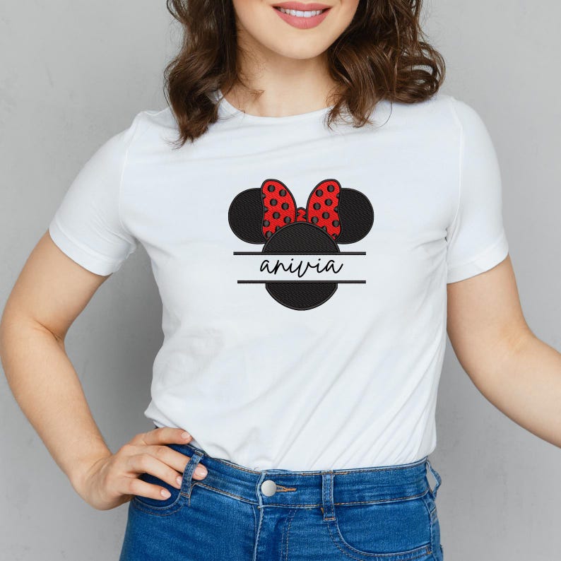 May include: White t-shirt featuring a black Minnie Mouse design with a red polka dot bow. The design includes the name "anivia" in a white font, centered below the bow.
