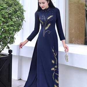 May include: A navy blue, long-sleeved dress with gold embroidery. The dress features a high neckline with bead embellishments and a split skirt. The image also shows a small, beaded purse and white shoes. The dress is elegant and suitable for formal occasions.