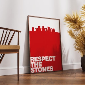 Może przedstawiać: Oprawiony wydruk artystyczny z czerwonym tłem i białym tekstem: "RESPECT THE STONES". Górna część przedstawia czerwoną sylwetkę Stonehenge. Wydruk jest prezentowany na drewnianej podłodze. Rama jest brązowa.