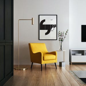 Könnte beinhalten: Ein modernes Wohnzimmer mit einem gelben Sessel mit schwarzen Beinen, einer goldenen Stehlampe und einem gerahmten Schwarz-Weiß-Poster. Ein kleiner Beistelltisch trägt eine Vase mit Blumen. Der Raum hat Holzböden und eine neutrale Farbpalette.