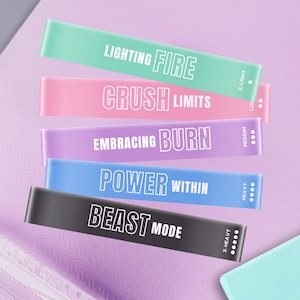 May include: A collection of colorful resistance bands with motivational phrases: "LIGHTING FIRE", "CRUSH LIMITS", "EMBRACING BURN", "POWER WITHIN", and "BEAST MODE". Each band is a different color, with text in white. The bands are labeled with resistance levels.