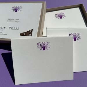 May include: A set of white flat cards with a purple floral design in a box. The box is open, revealing the cards and the text "SALTBOX PRESS". The cards are arranged on a purple surface.